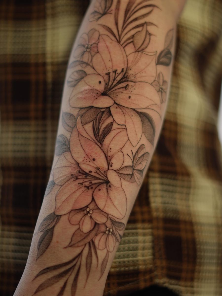 Fine-line lilies climbing a forearm