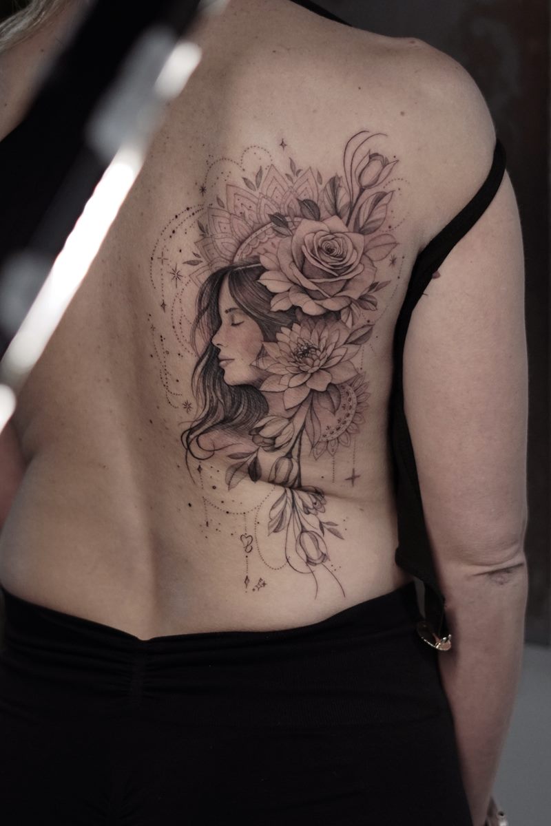 Black and grey portrait of a woman framed by roses, tattooed on the back